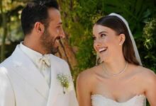 Bride and groom smiling at each other outdoors on their wedding day, greenery in the background.