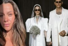 Close-up of a woman with long brown hair; in the background, a bride in a white gown with a bouquet and a man in a white suit standing together.
