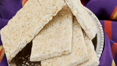 Slices of sesame brittle arranged on a plate, with a purple cloth in the background, showing crunchy textured bars