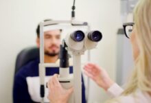 Optometrist uses a slit lamp to examine a patient’s eyes during an eye exam.