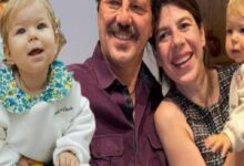 Smiling couple holds two young children for a group photo: girl on the left and a baby on the right.